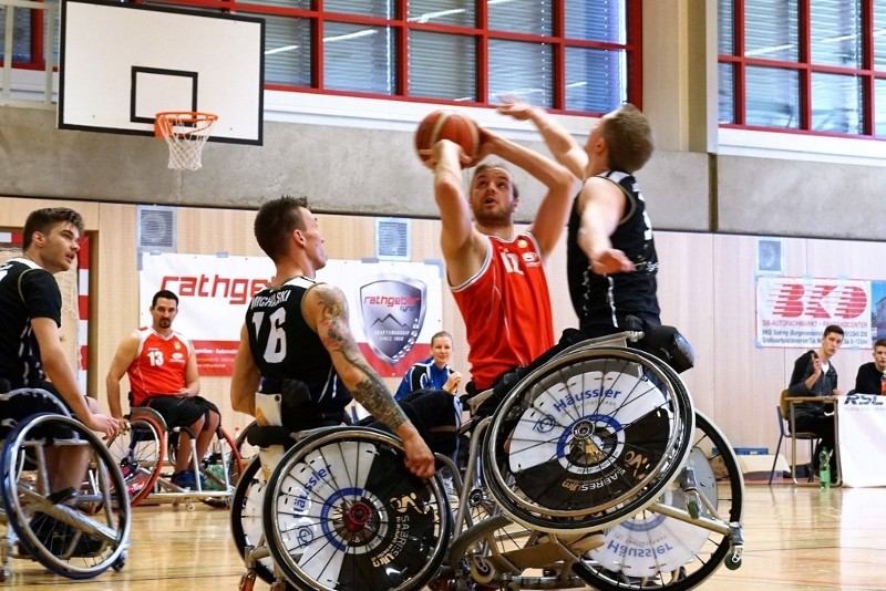 Das gegnerische Team versucht, den Wurf vom Tiroler Rollstuhlbasketballspieler ins Netz zu verhindern 