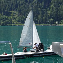 Rollstuhlfahrer im Segelboot der Klasse 2,4mR mit Segeltrainer am Achensee in Tirol.