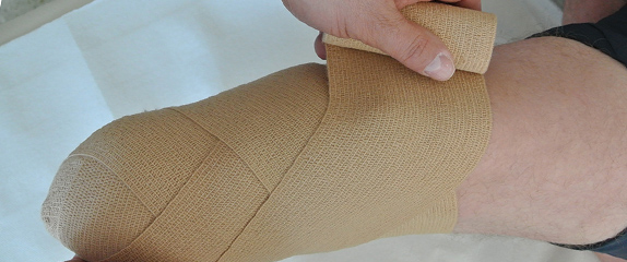 Einem Patienten wird nach einer Amputation am Unterschenkel eine fachgerechte Stumpfbandage angelegt