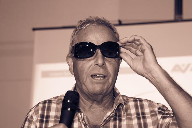 Ein schwarzweißes Profilbild vom ehemaligen Physioleiter Richard Altenberger. Er trägt ganz cool eine schwarze Sonnenbrille. In der Hand hält er ein Mikrofon.